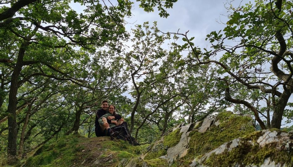 Meine Frau und ich sitzen auf einem Felsgrat im Nationalpark Eifel umgeben von verschlungenen Eichen.