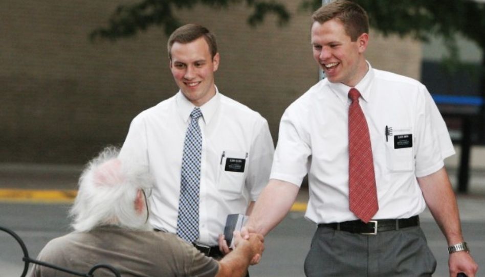 Zu sehen sind zwei Missionare der Kirche Jesu Christi. Sie begrüßen freundlich einen Mann.