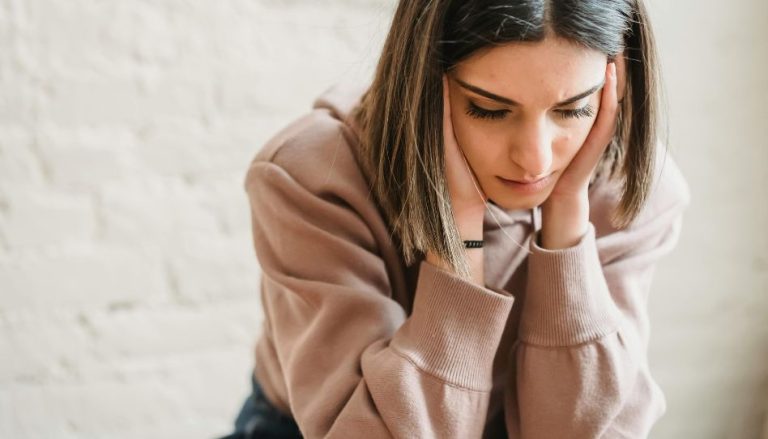 Zu sehen ist eine junge Frau. Sie hat ihren Kopf in den Händen und schaut nach unten. Sie soll jemanden darstellen, der zweifelt und dessen Vertrauen verloren ging.