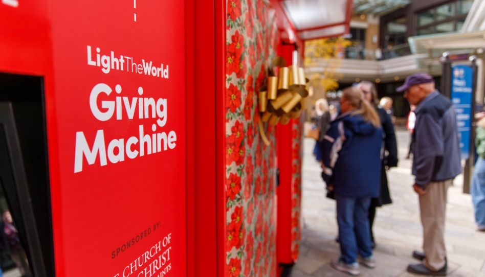 Eine Giving Machine mit dem Schriftzug „Light the World“ zieht die Aufmerksamkeit von Passanten auf sich.