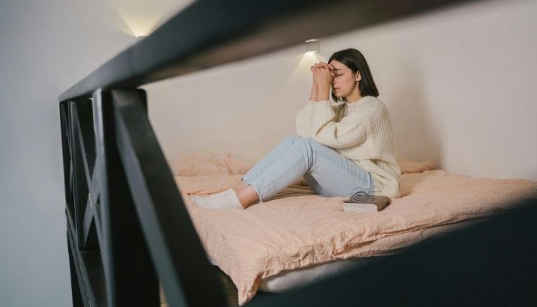 Eine Frau sitzt auf dem Bett und betet.