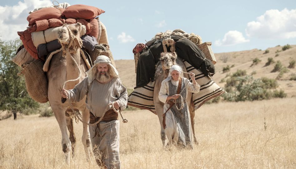 Lehi flieht mit seiner Familie von Jerusalem in die Wildnis. Hier sind er und seine Frau Saria mit bepackten Kamelen zu sehen.