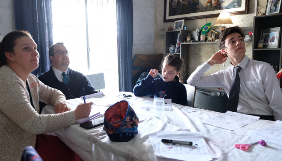 Eine Familie schaut zusammen die Generalkonferenz und macht nebenbei Notizen.