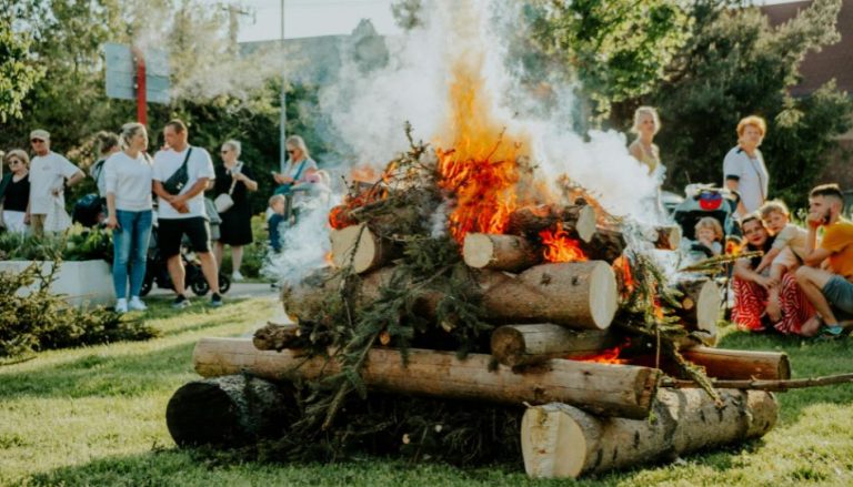 Menschen stehen in der Nähe eines Pfingstfeuers.