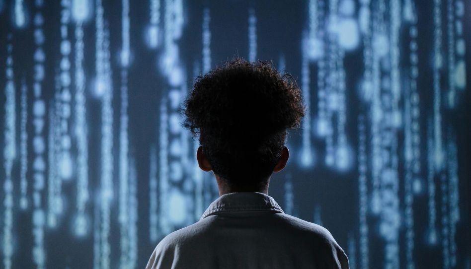 Ein Jugendlicher blickt auf eine Wand aus digitalen Datenlinien – ein starkes Bild für die Frage, wie KI den Schulalltag beeinflusst.